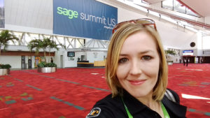 Jenn in front of Sage Summit banner